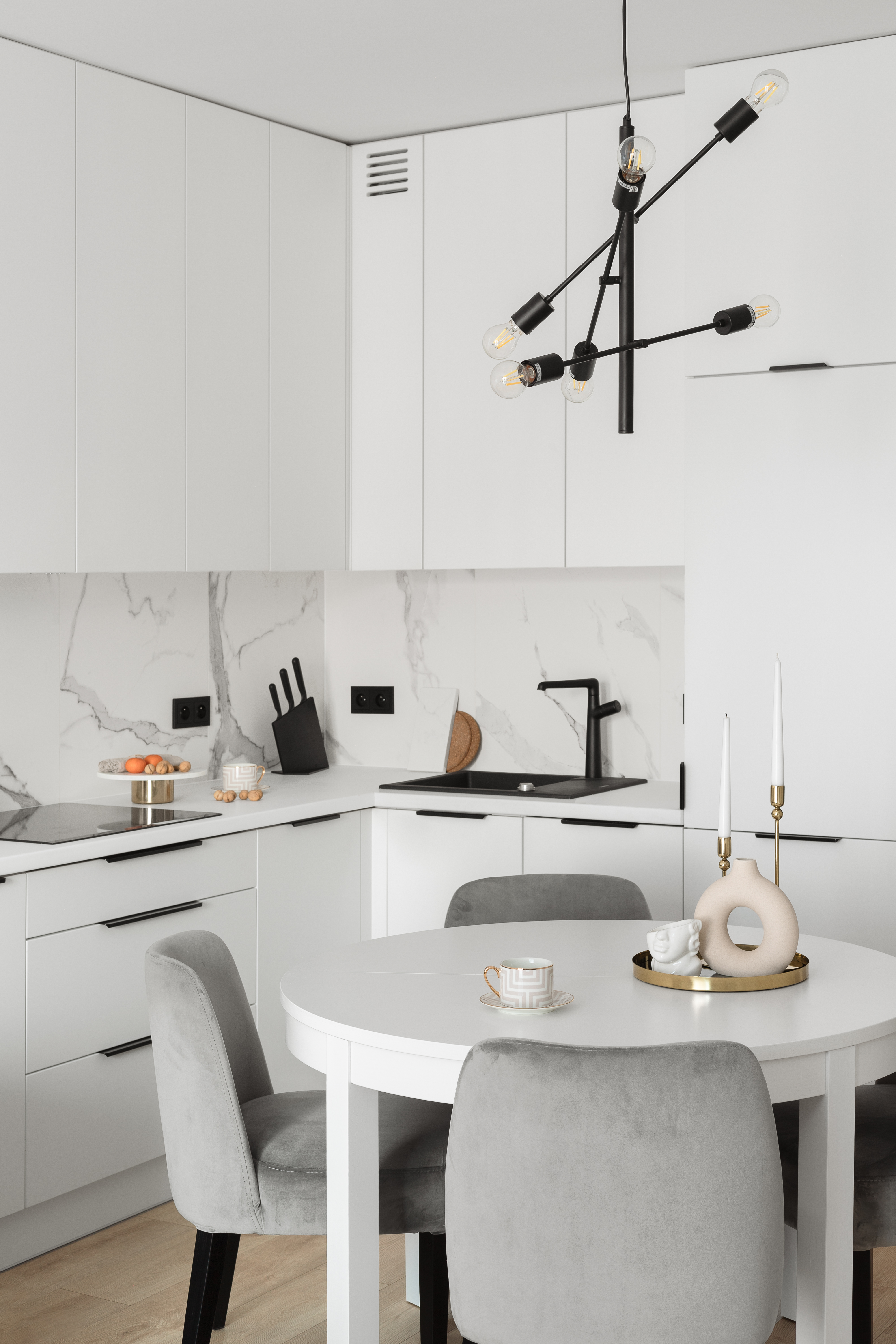 nowoczesne mieszkanie modern classic okrągły biały stół biała kuchnia z marmurem biały blat czarne uchwyty projektant wnętrz Gdańsk Olsztyn Iława Elbląg